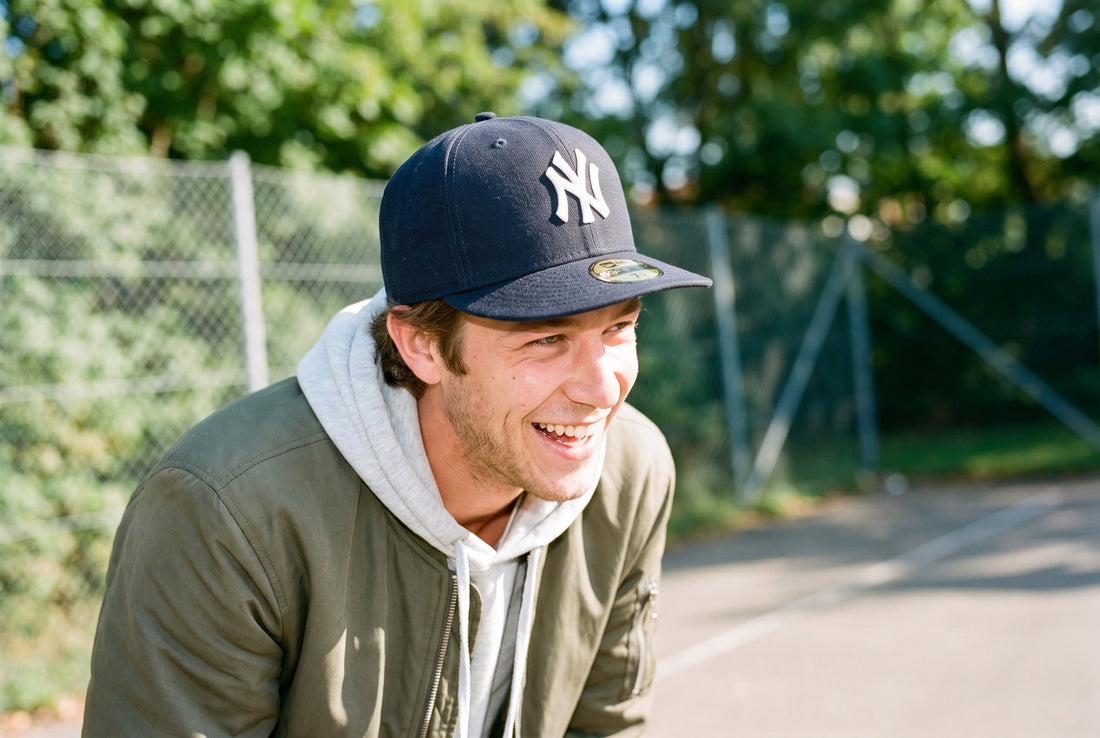Lachender Mann mit marineblauer New Era 59FIFTY mit weißem NY-Logo, flachem Schirm und Schirmsticker auf einem sonnigen Basketballplatz