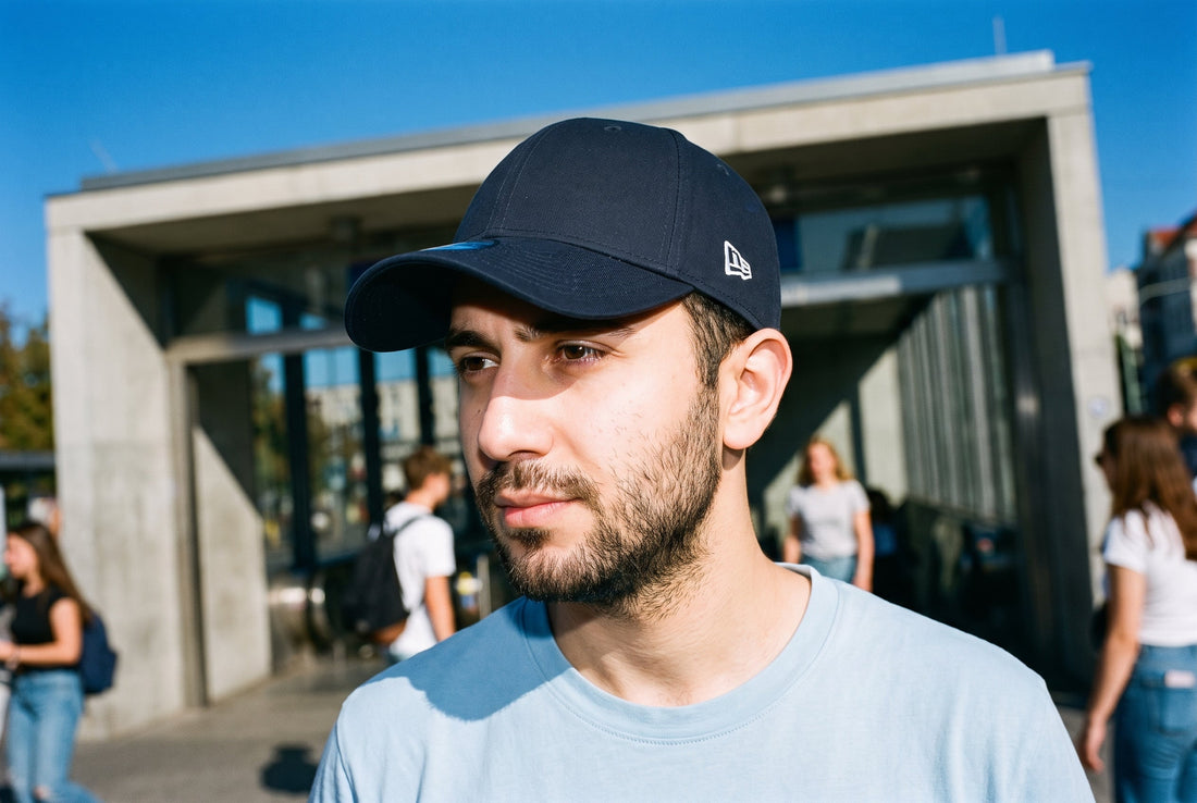 Mann mit marineblauer New Era 9FORTY, klassisch mit dem Schirm nach vorn getragen, vor einem U-Bahn-Eingang