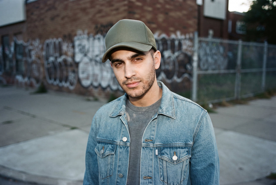 Mann mit unifarbener Trucker Cap vor Graffiti-Wand – New Era Cap Modelle im Vergleich