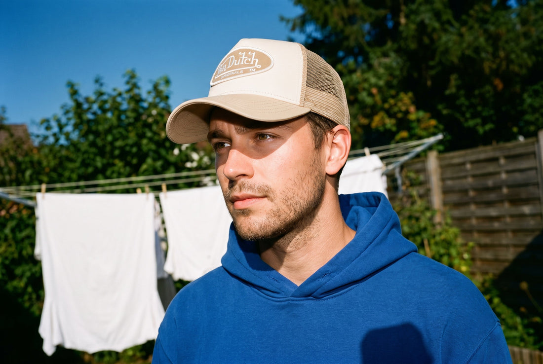 Mann mit beiger Von Dutch Trucker Cap neben einer Wäscheleine mit frisch gewaschener Wäsche
