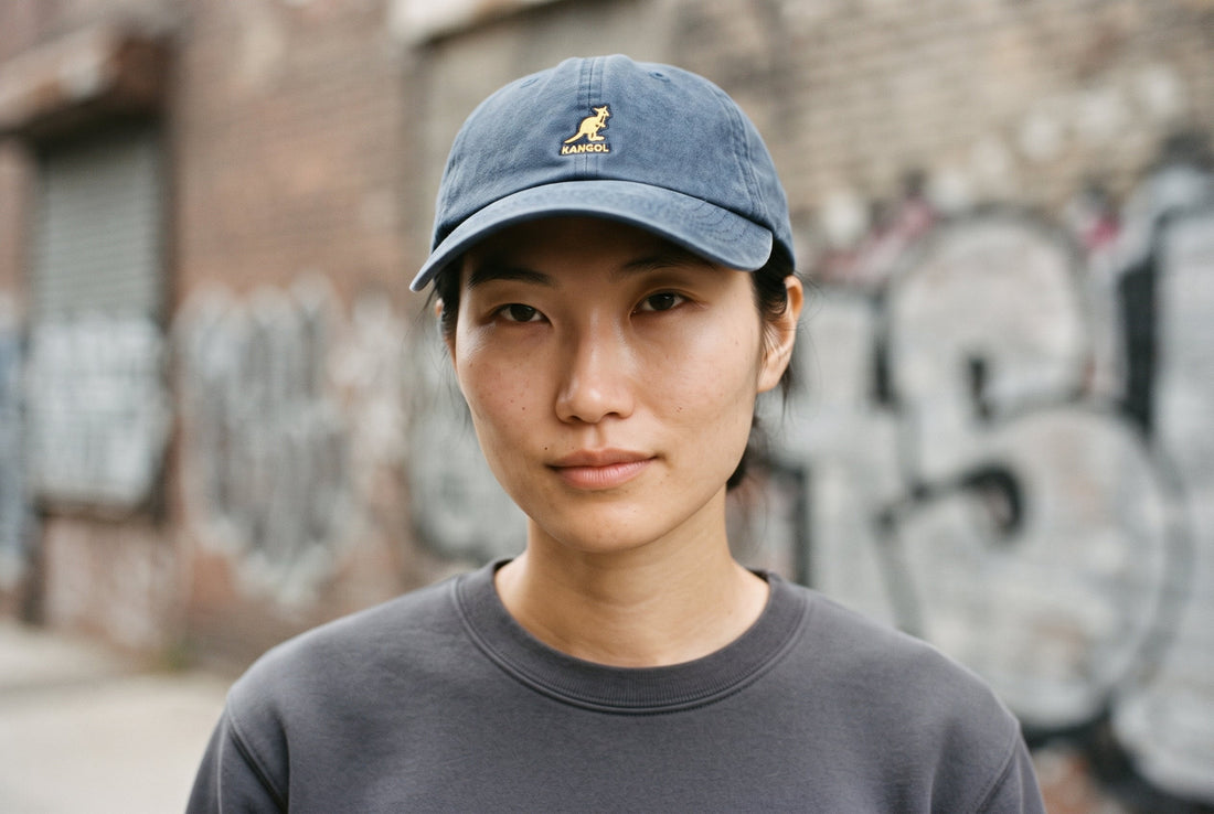 Frau mit marineblauer Kangol Washed Dad Hat mit weicher Front und gebogenem Schirm vor einer Graffiti-Wand